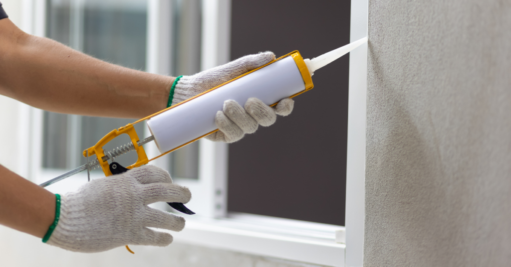 person caulking exterior of a window